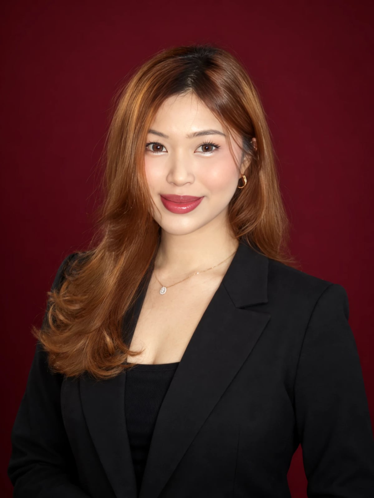 Ericha Ameilia Putri in a black blazer against a deep red backdrop